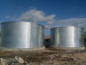 
	Модульні резервуари для води виробляють в найближчому зарубіжжі. На території України є компанія "ЕкоТанк", яка входить до группи компаній ТОВ "Екохаус" та поставляє резервуари для пожежного запасу води, питних потреб і емкості для КАС.

	&nbsp;&nbsp;

	В час нових технологій, завдання, що стоять в проектах, необхідно вирішувати виходячи з нових можливостей, а не по-старому, як дуже часто ми це зустрічаємо. Для цього треба брати на озброєння: світовий досвід і здоровий глузд. Ми відповідальні за впровадження нових рішень в галузі будівництва і рішення самих нестандартних завдань.

	З кожним роком, все гостріше постає питання з експлуатацією залізобетонних резервуарів в системах водопостачання. Більшість резервуарів перевищують нормативні терміни експлуатації, і знаходяться в аварійному стані. У той час, коли проектувалися залізо-бетонні резервуари фахівці виходили з технологій і можливостей того часу. Зараз полімерне і металеве виробництво знаходиться на новому високому рівні, дозволяючи з легкістю і меншими бюджетами вирішити складні завдання.

	
	Наша компанія знайшла рішення по виробництву резервуарів об'ємом до 4000м3. Взявши багаторічний досвід наших європейських сусідів, які використовують технологію будівництва модульних резервуарів вже більше 30 років. За допомогою наших інженерів ми допрацювали, удосконалили і адаптували цю технологію до наших умов. Зараз ми можемо запропонувати наші швидко-збірні метало-пластикові резервуари: висотою від 1 метра до 10 метрів і діаметром від 4 метрів до 32 метрів. Резервуари підходять для питної і технічної води, а також різних агресивних розчинів, виробляємо їх згідно нашого ТУ У 22.2-36115081-001:2017. Резервуар має багато переваг: по-перше, в розібраному вигляді величезна ємність займає незначне місце, зібрати можливо в будь-якому важкодоступному місці. Час монтажу ємності 3000м3 - 28 днів. Монтувати резервуар можливо в будь-який час року навіть взимку і в дощ. Монтаж не вимагає ніякої вантажопідйомної техніки. Резервуар легко обслуговувати, ремонтувати й спостерігати. При необхідності можливо демонтувати і встановити в новому місці.

	Це все можливо завдяки технології і поєднанню характеристик металу і пластика. Оцинкований корпус тримає воду, а пластиковий вкладиш контактує з рідиною.

	Нормативний термін служби наших ємностей 30 років. З 2010 року ми почали монтувати метало-пластикові резервуари в Україні. За цей час змонтовано близько чотирьох сотень резервуарів різних розмірів. За кожним з них ми ведемо спостереження. Після п'яти років ємності добре себе показали. Наприклад, у м Ічня змонтовано дві ємності для КАС по 1200м3 (карбамідно-аміачна суміш), це дуже агресивна рідина, і після п'яти років експлуатації ємності в чудовому стані.

	Технологія зведення резервуара:

	Бетонна основа під резервуар. Наші ємності можуть встановлюватися на стрічкову бетонну основу якщо ми не маємо справу зі складними грунтами.

	Металевий корпус ємності виготовлений з оцинкованої гофрованої сталі. Гофрування збільшує в кілька разів жорсткість каркаса. Наприклад, ємність з гофрованого металу товщиною 1 мм. по жорсткості дорівнює ємності з &laquo;гладкого&raquo; металу товщиною 4-5 мм.

	Технічні характеристики металу:

	
		
			
				
					Показники
			
			
				
					Одиниці виміру
			
			
				
					Значення показників
			
		
		
			
				
					Товщина
			
			
				
					мм.
			
			
				
					1-4
			
		
		
			
				
					Приділ тікучості
			
			
				
					N/mm2
			
			
				
					350
			
		
		
			
				
					Приділ міцності
			
			
				
					N/mm2
			
			
				
					420
			
		
		
			
				
					Покриття цинком
			
			
				
					г/м2
			
			
				
					275
			
		
	


	&nbsp;

	Каркас кожної ємності та болтові з'єднання розраховані з мінімальним запасом міцності - 1,5. Середній запас міцності - 2.

	З'єднуються листи між собою на спеціальних болтах, які мають найвищий клас міцності. Крім цинкування, болти додатково покриті кобальтом, що мінімум на 5 років збільшує термін їх експлуатації.

	Всередину каркаса, між вкладишем і оцинкованими листами, а також на дно ємності встановлюється захисна тканина. В якості захисної тканини застосовується водостійкий геотекстиль високої щільності. Геотекстиль перешкоджає тертю і стиранню вкладиша об дно або металеві стіни ємності. Товщина геотекстилю - 1 мм.

	Вкладиш ємності, виготовлений з високоміцного поліпропілену. Вкладиш перевіряється на герметичність надлишковим тиском і поставляється на об'єкт готовим до експлуатації. Ніякі роботи зі зварювання вкладиша на об'єкті не проводяться.

	Товщина мембрани - 0,5 або 1,5 мм. Ця товщина оптимальна, так як збільшення товщини мембрани погіршує гнучкість вкладиша, а зменшення погіршує міцність. В діапазоні товщини 0,5-0,75 мм. під навантаженням мембрана добре розтягується, а при знятті навантаження - повертається до початкових розмірів без зміни властивостей.

	Характеристики мембрани:

	
		
			
				
					Показники
			
			
				
					Одиниці виміру
			
			
				
					Значення показників
			
		
		
			
				
					Щільність
			
			
				
					&nbsp;g/cm3
			
			
				
					0,89
			
		
		
			
				
					Товщина
			
			
				
					&nbsp;мм.
			
			
				
					0,5-0,75
			
		
		
			
				
					Напруга при розриві
			
			
				
					MPa
			
			
				
					18
			
		
		
			
				
					Розтягування при розриві
			
			
				
					%
			
			
				
					250
			
		
		
			
				
					Опір при розриві
			
			
				
					N/mm2
			
			
				
					80
			
		
		
			
				
					Опір проколу
			
			
				
					N
			
			
				
					150
			
		
		
			
				
					Робоча температура
			
			
				
					Градусів Цельсія
			
			
				
					від -30 до +80
			
		
	


	Мембрана УФ-стабілізована, може застосовуватися для зберігання питної води, харчових продуктів і слабоагресивних речовин. Колір чорний. Гарантія від виробника 10 років.

	Дах ємності. Резервуари комплектується металевим або пластиковим дахом. Крім того, ємності можуть виготовлятися без даху.

	Металевий дах витримує снігове навантаження і встановлюється на ємності цілорічної експлуатації. Металевий дах складається з несучого каркаса (оцинкованих ферм), які кріпляться до каркасу ємності, і настилу з оцинкованих листів або профнастилу. З'єднуються між собою листи настилу саморізами з гумовими шайбами.

	Технічні характеристики металевих дахів:

	
		
			
				
					Показники
			
			
				
					Одиниці виміру
			
			
				
					Значення показників
			
		
		
			
				
					Діаметр даху
			
			
				
					м
			
			
				
					від 3,7 до 32
			
		
		
			
				
					Матаріал настилу
			
			
				
					&nbsp;
			
			
				
					оцинкований лист або профнастил
			
		
		
			
				
					Товщина настилу
			
			
				
					мм
			
			
				
					0,75 - 1
			
		
		
			
				
					Снігове навантаження
			
			
				
					кг/м2
			
			
				
					180
			
		
		
			
				
					Комплектація
			
			
				
					&nbsp;
			
			
				
					Ревізійний люк, мотузяна драбина
			
		
	


	Пластиковий натяжний дах встановлюється на ємності, які експлуатуються всередині приміщення або сезонно на вулиці. Пластиковий дах кріпиться до верхнього ряду оцинкованих листів каркаса через люверси і мотузку. Цей дах запобігає потраплянню в ємність бруду, пилу, комах, дощової води. Пластиковий даху діаметром більше 7,3 метра додатково комплектуються центральним опорним стовпом.

	Діаметр натяжних дахів - від 3,7 до 32 метрів.

	У деяких випадках дах на ємність не потрібен. Як правило, встановлюються без даху ємності для поливу (особливо в теплицях), ємності збору дощової води, збору стічних вод, сезонні ємності для води.

	Обв'язка резервуара

	Надходження або забір води в ємність здійснюється або через дах (введення труби без відведення), або через бічний відвід, зроблений у верхній частині ємності. Або через дно якщо потрібно підключення великого діаметру.

	Якщо необхідний повний слив ємності, або діаметр зливного відводу більше 160 мм., Встановлюється донний злив ємності. Через дно в ємність заводиться труба (метал, ПВХ, ПЕ, ПП). Діаметр донного відведення не обмежений.

	Перелив здійснюється через бічний відвід. Це патрубо, який монтується під дахом резервуара, та знаходиться вище інших підключень і закінчується фланцем.

	Крім базового комплекту обв'язки, встановлюються поплавки, люки, крани, вентиляційні патрубки, сходи, мірна шкала, насоси, будь-які датчики та інші елементи обв'язки, необхідні Замовнику.

	Утеплення та підігрів

	Для експлуатації ємності в зимовий період застосовуються утеплення і підігрів ємності. Необхідність утеплення або підігріву, товщина утеплювача, потужність підігріву визначаються виключно тепловим розрахунком. Виходячи з практичного досвіду, виділимо наступне:

	1)&nbsp;якщо здійснюється часте оновлення води в ємності (раз в два-три дня частково зливається і заливається нова вода), то підігрів і утеплення не потрібні. Ємності в системі централізованого водопостачання населених пунктів ніколи не утеплюються, так як йде постійна циркуляція води;

	2)&nbsp;якщо оновлення води здійснюється не рідше одного разу на 7-10 днів, для запобігання замерзання води необхідно утеплити ємність.

	3)&nbsp;якщо оновлення води здійснюється рідше одного разу на 10 днів і ємність експлуатується в зимовий період, необхідно утеплення і підігрів води. Виходячи з цього, наземні пожежні резервуари потрібно не тільки утеплювати, а й ставити систему підігріву.

	Для утеплення бічної поверхні і даху застосовується пінополістирол високої щільності (80-110 кг. / М3) завтовшки 50-140 мм.

	Система підігріву рідини в ємності складається з Тена (або заглибних теплових кабелів), датчиків температури і системи управління. Коли згідно датчику температура опускається до мінімальної (як правило, +1 градус Цельсія), включається ТЕН. Після збільшення температури на 1-2 градуси датчики відключають ТЕН.

	Потужність Тена коливається в межах від 4 до 12 кВт. Енерговитрати невеликі, так як в утеплених ємностях Тени працюють в сукупності не більше 1 місяця в році.

	Великі сталеві резервуари чистої води, які вже експлуатуються в системі водопостачання різних населених пунктах:

	- 800 м3&nbsp;м. Ічня "Водоканал"

	- 2000 м3&nbsp;м. Білгород-Дністровский "Водоканал"

	- 2200 м3 с. Велика Михайлівка (Одесская обл)

	- 2300 м3&nbsp;м. Тернівка (Дніпропетровська обл) "Водоканал"

	- 5000 м3&nbsp;м. Слав'янськ &laquo;Водоканал&raquo;

	

	"ЕкоТанк" группа компаній ТОВ "ЕКОХАУС"

	г. Киев б. Л. Курбаса 2-Б, оф. 702

	Тел.: +38(067)-236-54-77

	&nbsp; &nbsp; &nbsp; &nbsp; &nbsp;+38(044)-332-07-57&nbsp;

	&nbsp; &nbsp; &nbsp; &nbsp; &nbsp;+38(067)-401-89-90

	E-mail: Ця електронна адреса захищена від спам-ботів. Вам необхідно увімкнути JavaScript, щоб побачити її.
				document.getElementById('cloakd91ac0ace1602999fb7fd58964f5f249').innerHTML = '';
				var prefix = 'ma' + 'il' + 'to';
				var path = 'hr' + 'ef' + '=';
				var addyd91ac0ace1602999fb7fd58964f5f249 = 'info' + '@';
				addyd91ac0ace1602999fb7fd58964f5f249 = addyd91ac0ace1602999fb7fd58964f5f249 + 'ecotank' + '.' + 'org';
				var addy_textd91ac0ace1602999fb7fd58964f5f249 = 'info' + '@' + 'ecotank' + '.' + 'org';document.getElementById('cloakd91ac0ace1602999fb7fd58964f5f249').innerHTML += ''+addy_textd91ac0ace1602999fb7fd58964f5f249+'';
		&nbsp; &nbsp; &nbsp; &nbsp; &nbsp;

	
		&nbsp;

